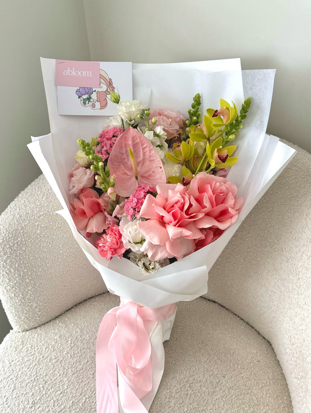 Bouquet of pink flowers with a card on a beige surface