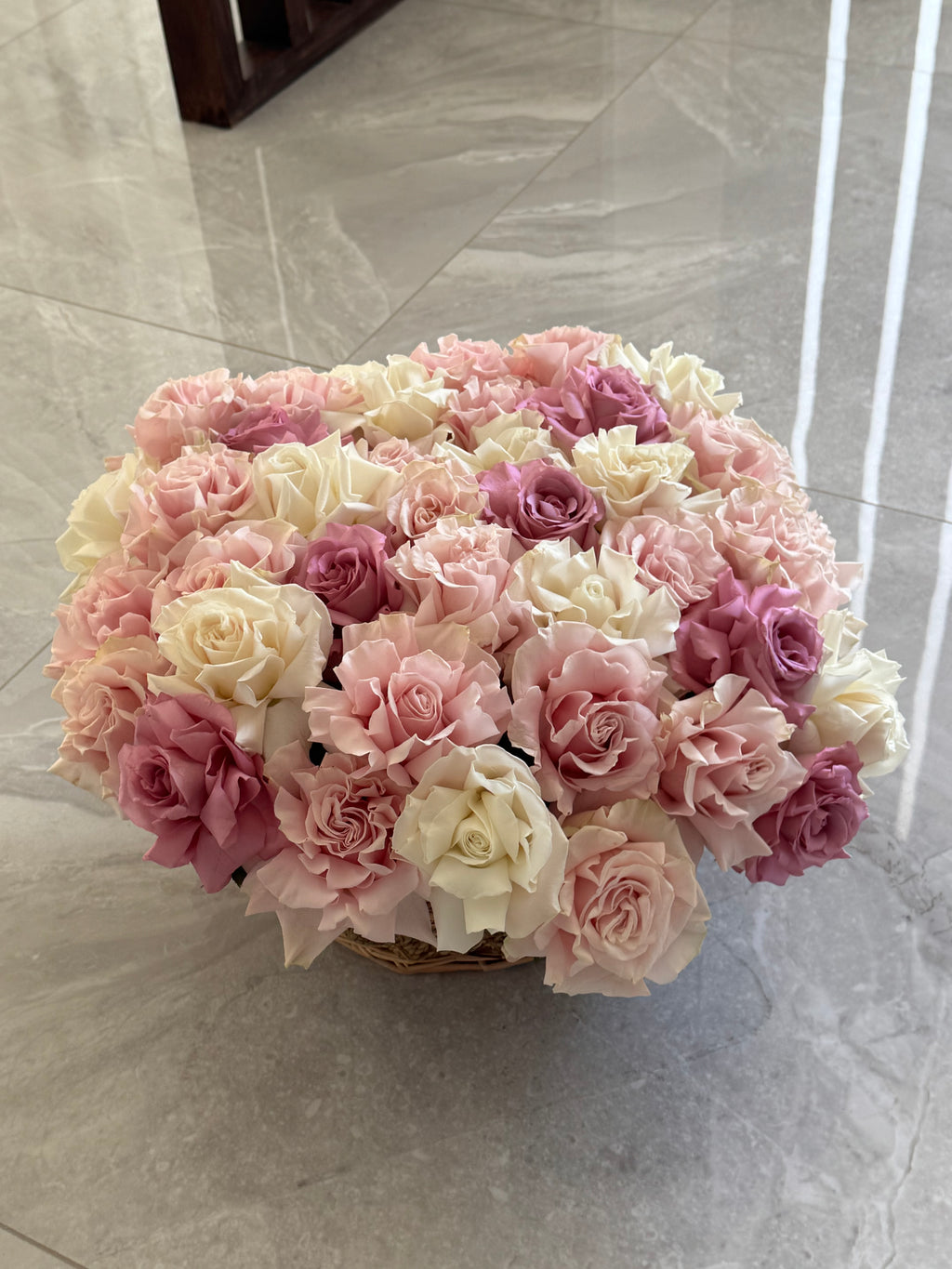 Bouquet of pink and white flowers on a marble surface, in woven basket